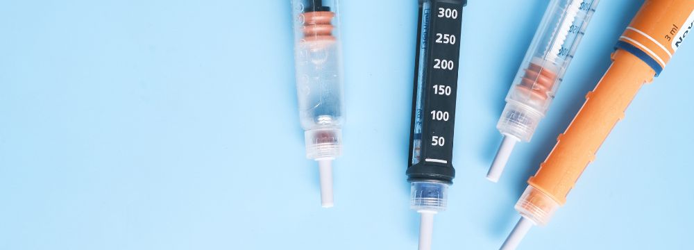 VAriety of weight loss injections scattered on light blue backdrop