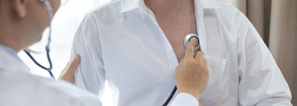 Dcotor listening to woman's heart using stethoscope