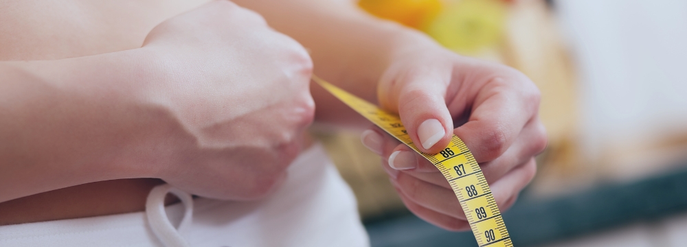 woman measuring was it size with yellow measuring tape